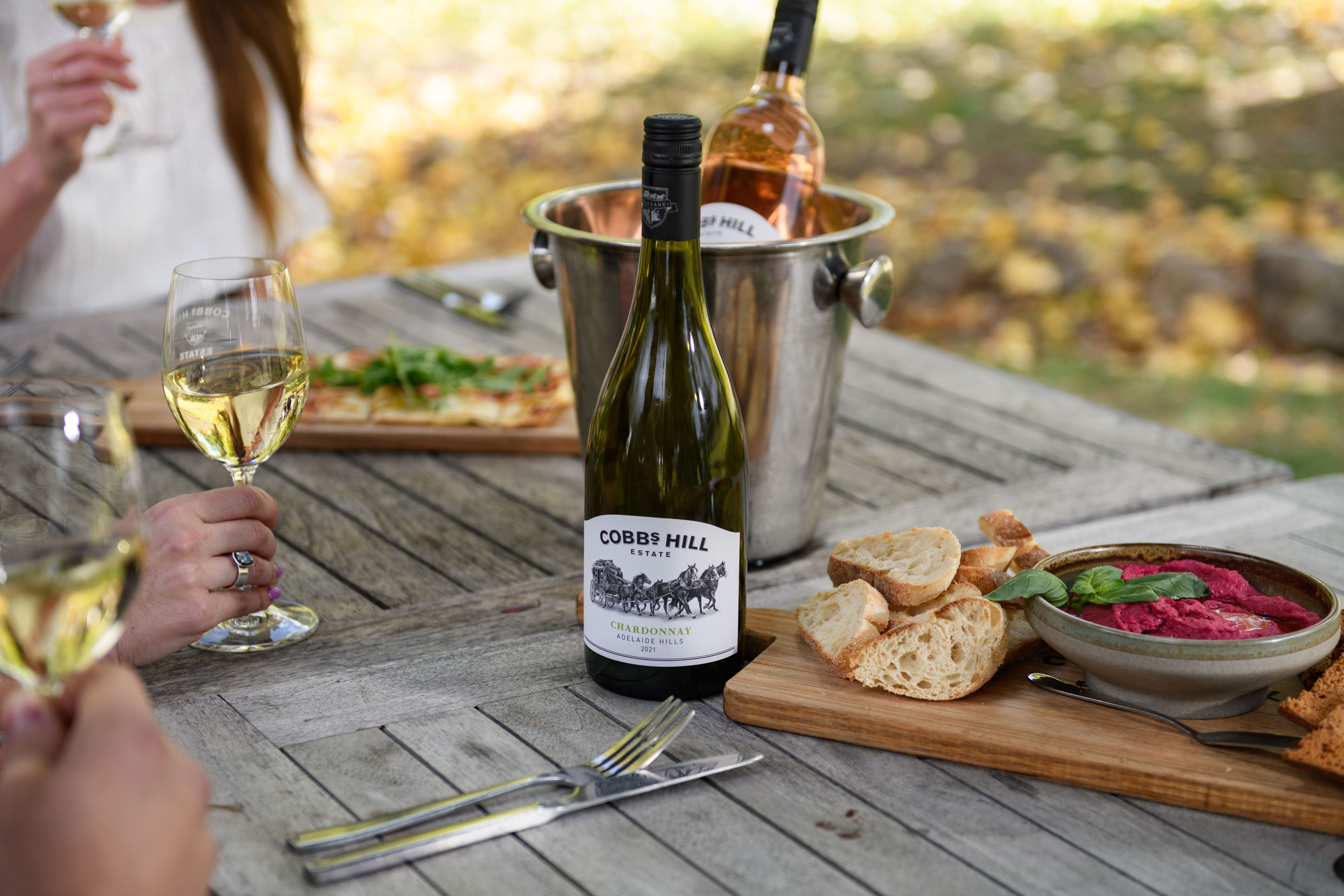 People at the picnic table enjoying wine and food 